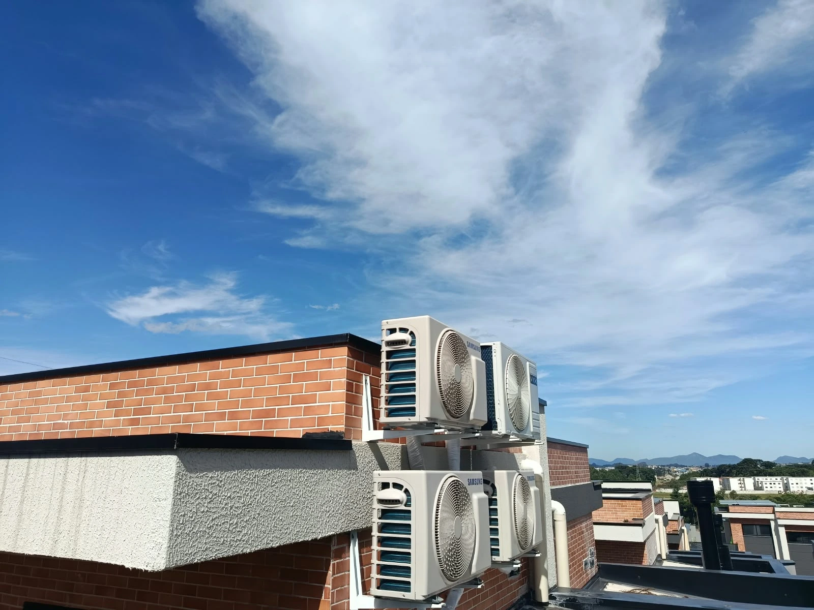 Unidades condensadoras de ar-condicionado instaladas em telhado residencial sob céu azul